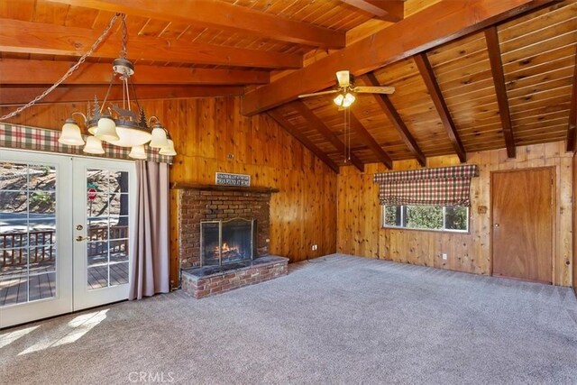 unfurnished living room with carpet flooring, wood walls, french doors, and a brick fireplace