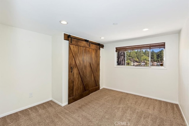 unfurnished bedroom with carpet and a barn door