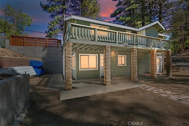 back house at dusk with a patio and a deck