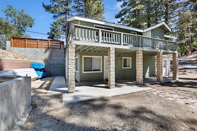 back of property featuring a wooden deck and a patio