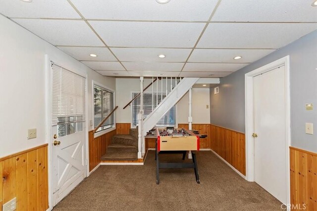 playroom with a drop ceiling, wooden walls, and carpet