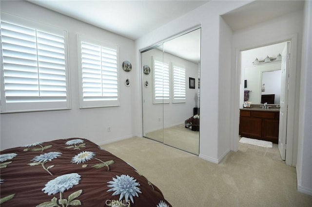 bedroom with sink, ensuite bathroom, a closet, and light carpet