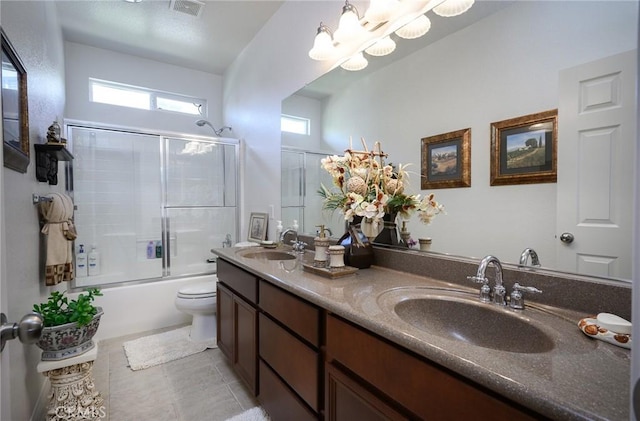 full bathroom featuring toilet, vanity, tile patterned floors, and bath / shower combo with glass door