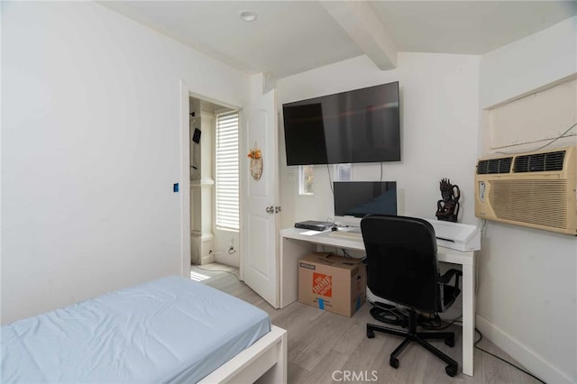 bedroom featuring beam ceiling, light hardwood / wood-style floors, and an AC wall unit