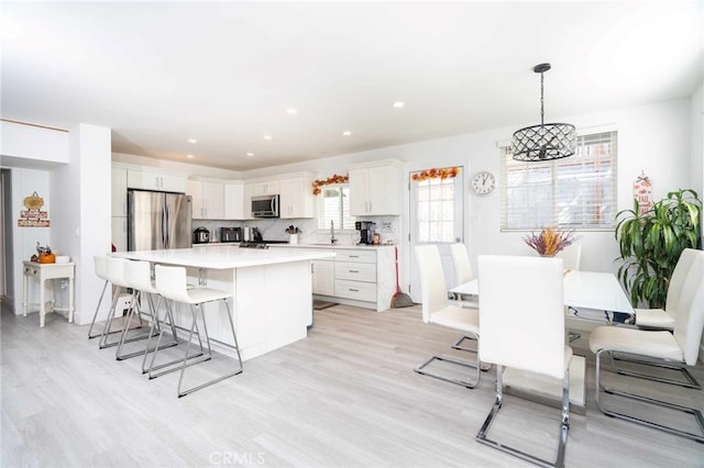 kitchen with hanging light fixtures, appliances with stainless steel finishes, a kitchen island, white cabinetry, and a chandelier