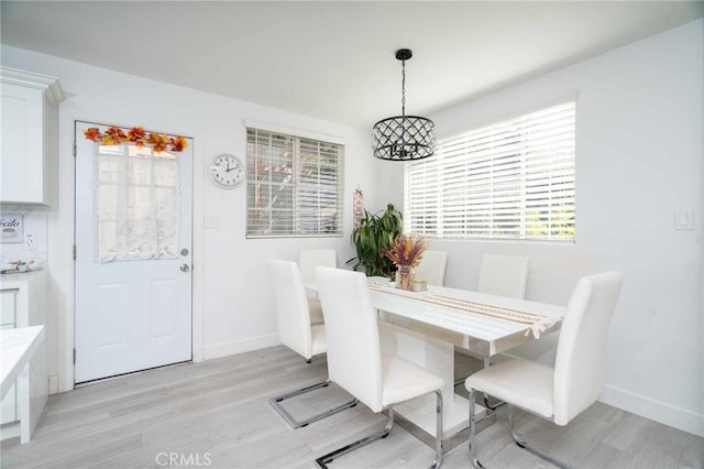 dining room featuring a notable chandelier, a healthy amount of sunlight, and light wood-type flooring