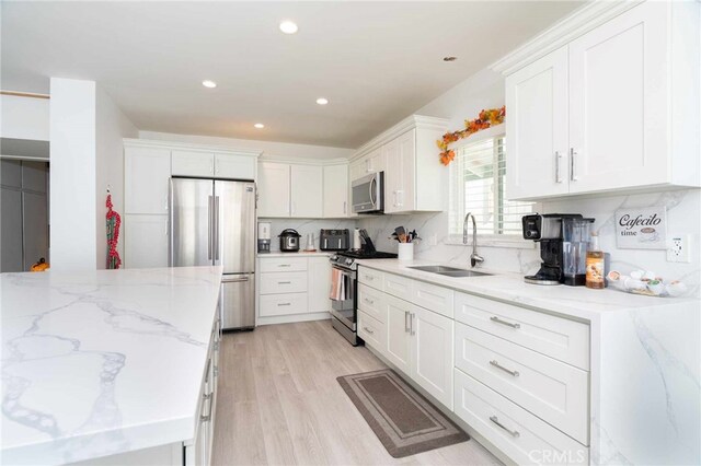 kitchen featuring white cabinets, sink, appliances with stainless steel finishes, tasteful backsplash, and light stone counters