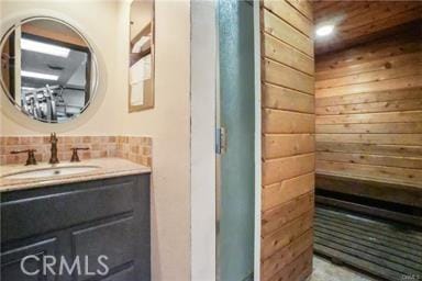 bathroom featuring wooden walls and vanity