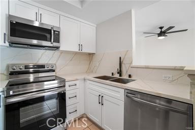 kitchen featuring white cabinetry, sink, ceiling fan, tasteful backsplash, and appliances with stainless steel finishes