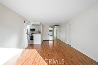 unfurnished living room featuring hardwood / wood-style flooring and ceiling fan