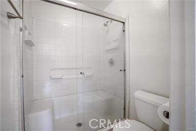 bathroom featuring toilet and a shower with door