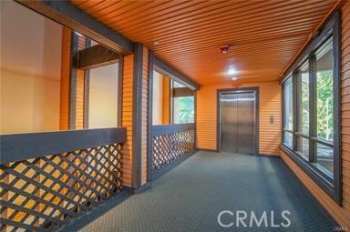 corridor featuring carpet flooring, elevator, and wood ceiling