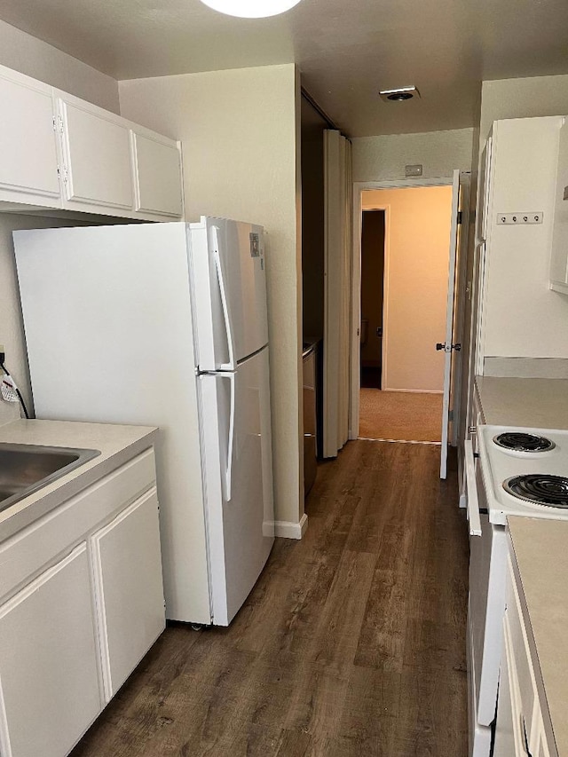 kitchen with white appliances, sink, dark wood-type flooring, and white cabinets