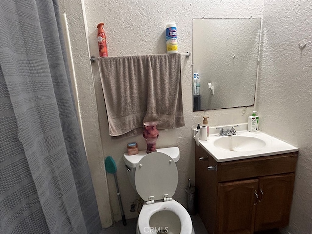 bathroom with walk in shower, vanity, and toilet