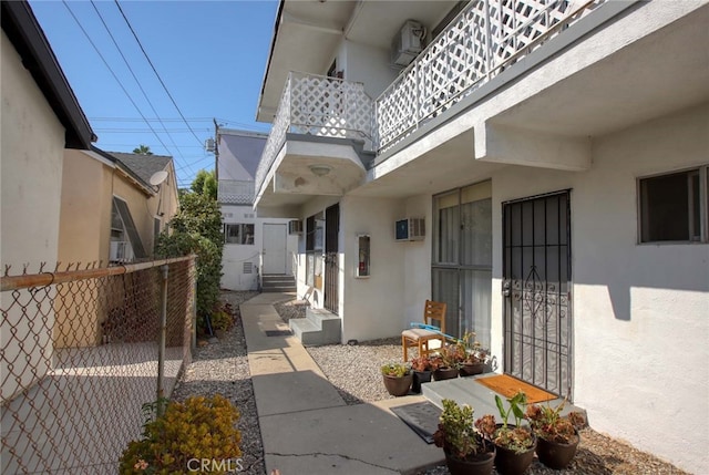 property entrance featuring a patio, a balcony, and a wall mounted air conditioner