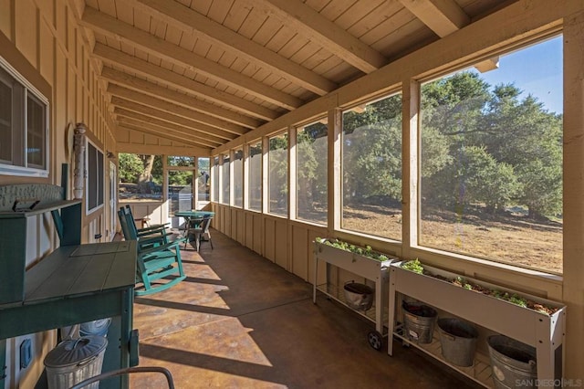 sunroom / solarium featuring vaulted ceiling with beams