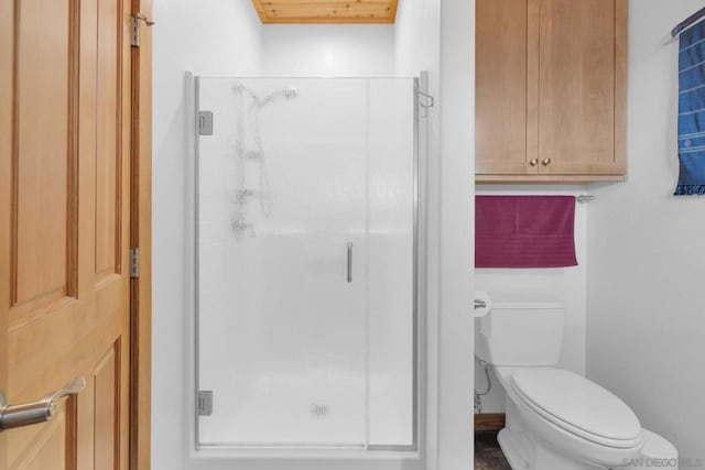 bathroom featuring a shower with shower door and toilet