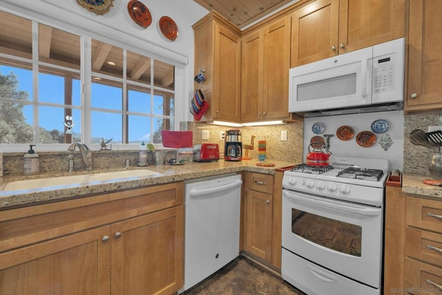 kitchen featuring decorative backsplash, white appliances, sink, and light stone counters