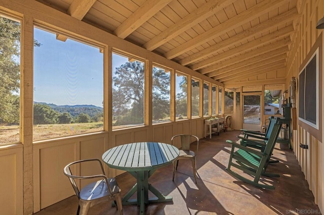 sunroom / solarium with vaulted ceiling with beams, plenty of natural light, and a mountain view