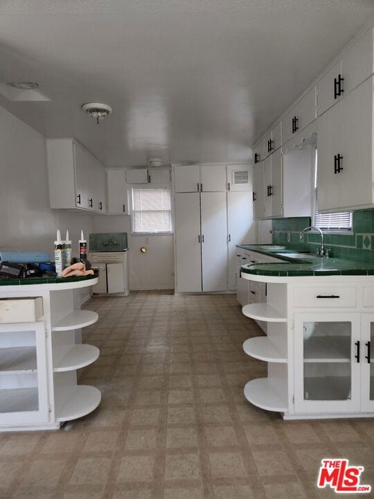 kitchen featuring backsplash, white cabinetry, and sink