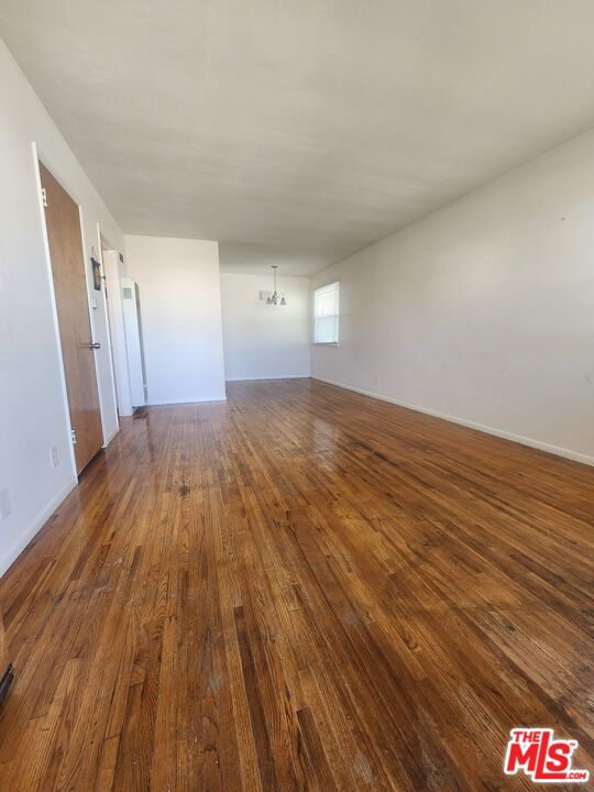 empty room with dark hardwood / wood-style floors and a chandelier