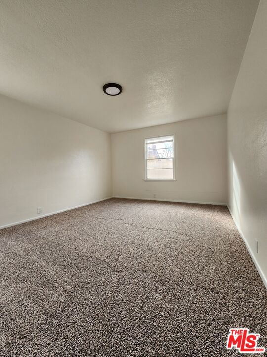 carpeted empty room featuring a textured ceiling