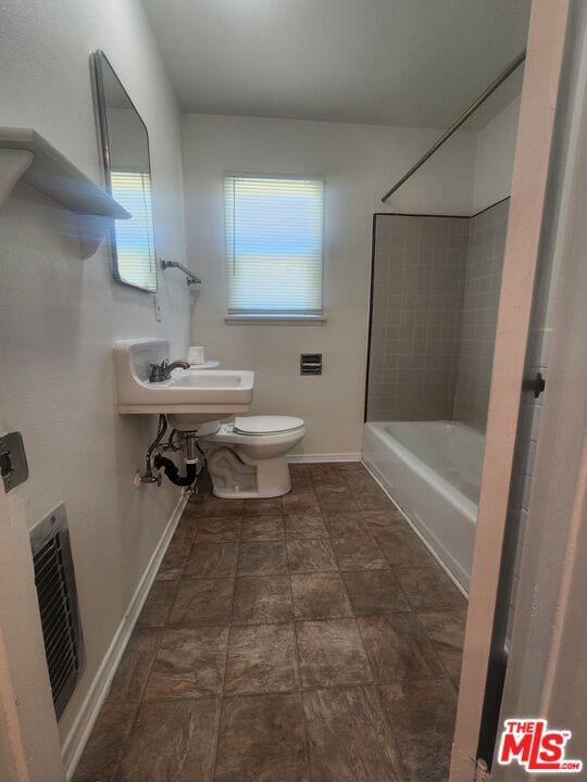 bathroom featuring tiled shower / bath combo and toilet