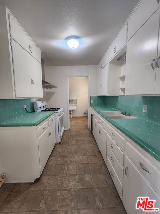 kitchen featuring white cabinets, tile counters, and white gas stove