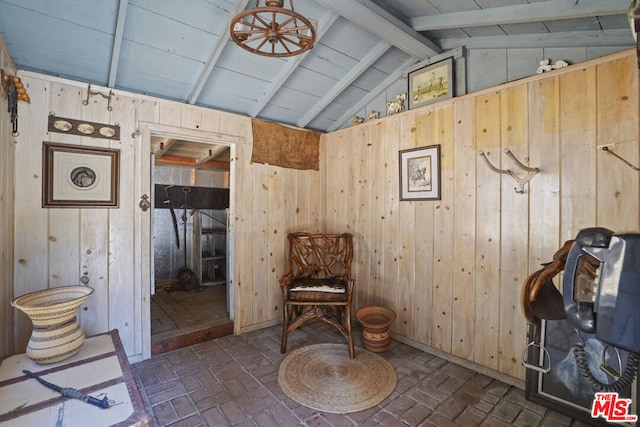 living area featuring lofted ceiling with beams and wood walls