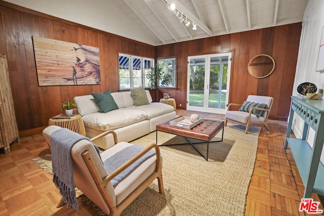 living room with wood walls, vaulted ceiling with beams, and track lighting