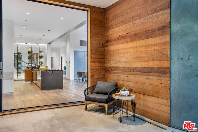 living area with light hardwood / wood-style floors and wooden walls