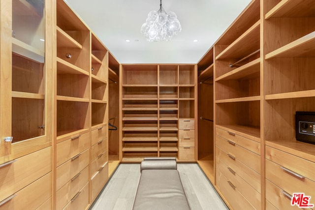 walk in closet with a notable chandelier and light hardwood / wood-style floors