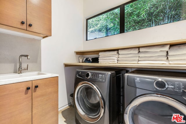 clothes washing area featuring sink, washer and dryer, and cabinets