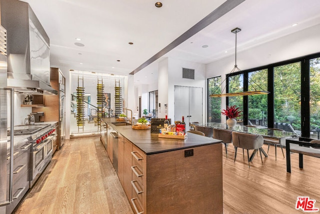 kitchen with hanging light fixtures, light hardwood / wood-style floors, sink, and extractor fan