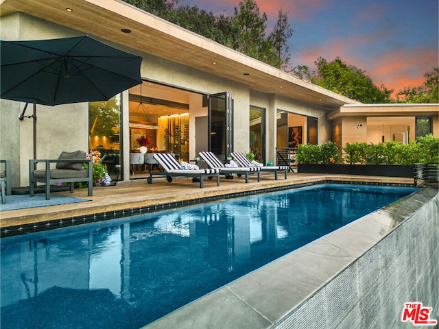 pool at dusk with a patio