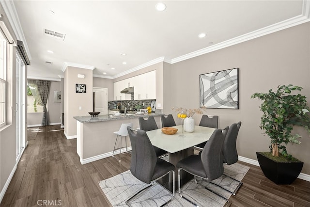 dining room featuring dark hardwood / wood-style flooring and crown molding