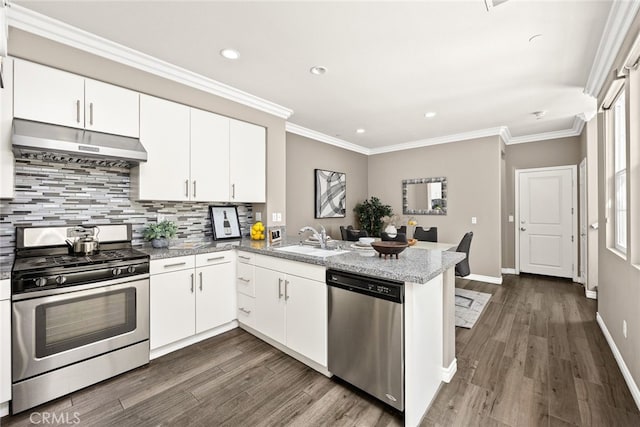 kitchen with extractor fan, sink, white cabinets, kitchen peninsula, and stainless steel appliances