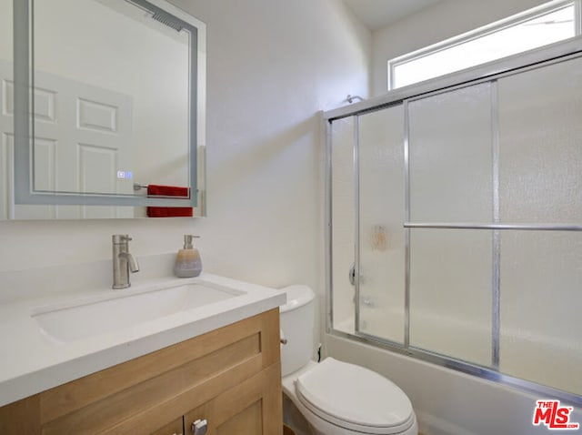 full bathroom with shower / bath combination with glass door, vanity, and toilet