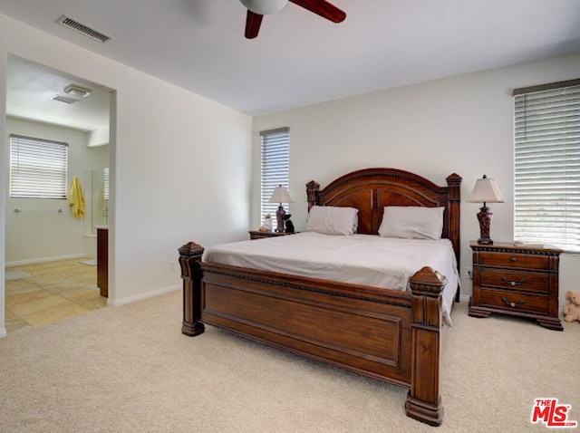 bedroom featuring light carpet, ceiling fan, and ensuite bathroom