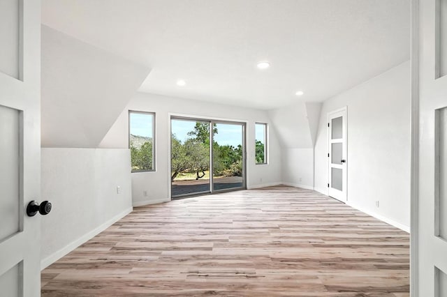 additional living space with lofted ceiling and light hardwood / wood-style flooring