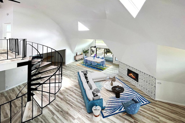 living room featuring vaulted ceiling with skylight, a fireplace, and hardwood / wood-style flooring