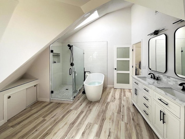 bathroom featuring plus walk in shower, hardwood / wood-style floors, vanity, and high vaulted ceiling