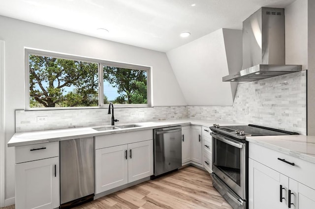 kitchen featuring appliances with stainless steel finishes, tasteful backsplash, wall chimney exhaust hood, and sink