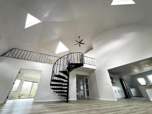 staircase featuring hardwood / wood-style flooring, ceiling fan, and a towering ceiling