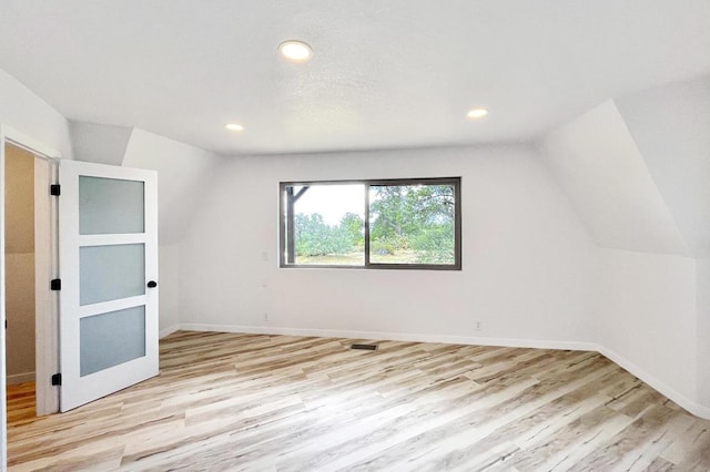 unfurnished bedroom with light hardwood / wood-style floors and lofted ceiling