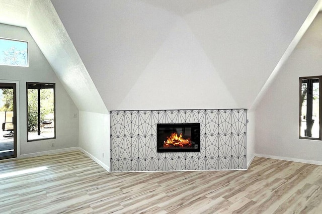 bonus room featuring plenty of natural light, light wood-type flooring, a fireplace, and lofted ceiling