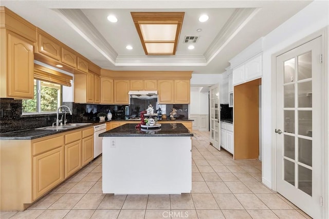 kitchen with light brown cabinets, white dishwasher, sink, a tray ceiling, and a kitchen island