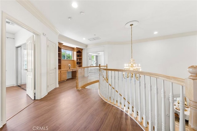 hallway with crown molding, wood-type flooring, and an inviting chandelier