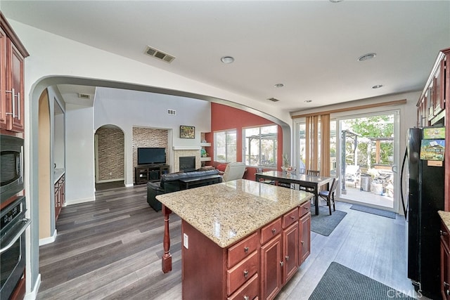 kitchen featuring a healthy amount of sunlight, black appliances, dark wood-type flooring, and a kitchen island