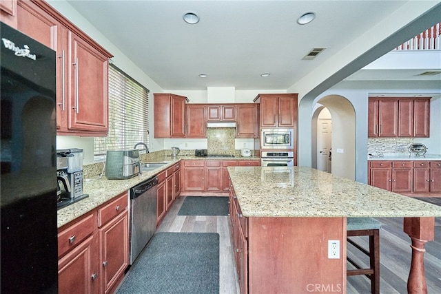 kitchen with dark hardwood / wood-style floors, black appliances, backsplash, and a center island